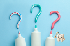 Three toothpaste tubes with colorful question marks above them on a blue background.