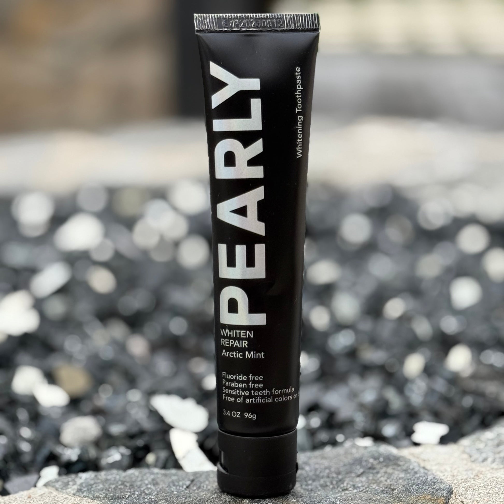 Black tube of Pearly on a stone surface with a blurred natural background